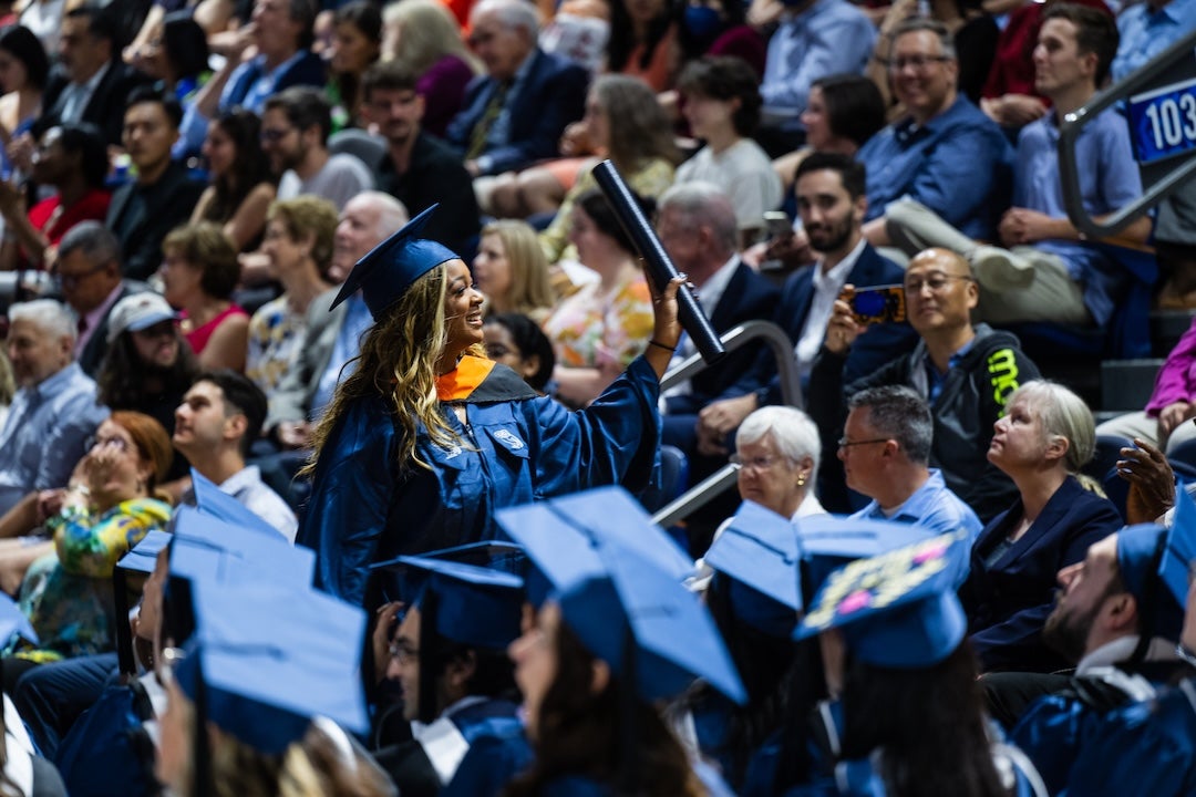 A female graduate waves to the crowd after receiving her diploma.