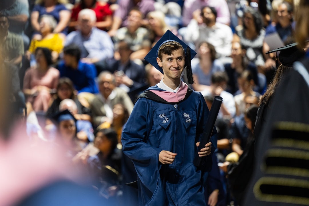 A male graduate from the Shepherd School of Music smiles after receiving his diploma.