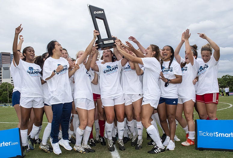 Rice players pose with the Conference USA trophy. (Photo by Tommy LaVergne)