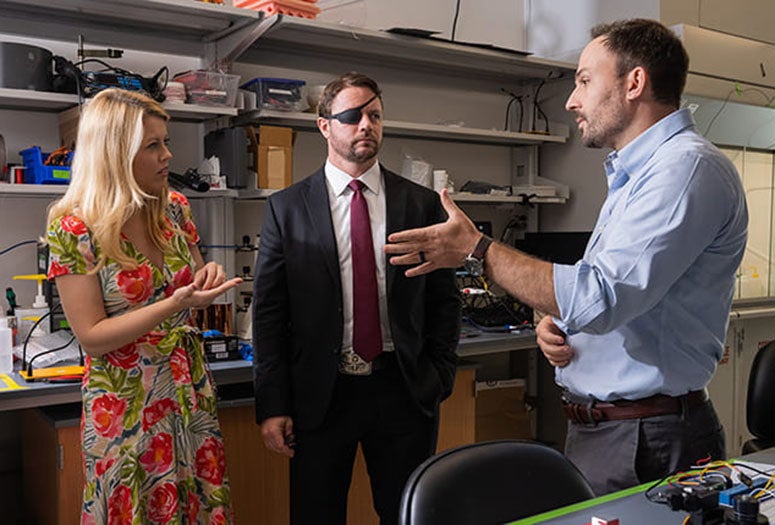 Jacob Robinson, associate professor of electrical and computer engineering and a core faculty member of Rice's Neuroengineering Initiative, discussed research with U.S. Rep. Dan Crenshaw (middle) and his wife, Tara Crenshaw(left), during a tour of neuroengineering research laboratories following Rep. Crenshaw's third annual Healthcare Innovation Summit July 23 at Rice's BioScience Research Collaborative.