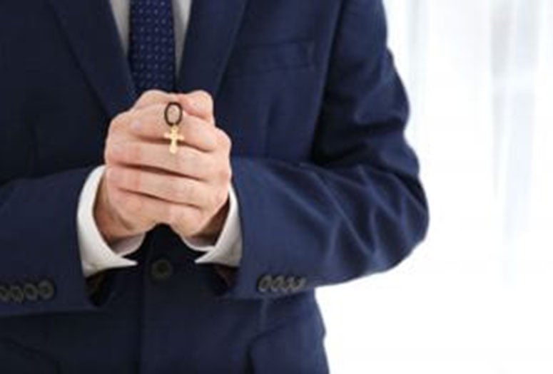 Man holding a golden cross in his hands. 