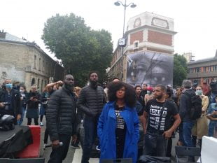 Adama Traoré's sister stands in front of a mural painted in France to honor Traoré and George Floyd. (Photo © Nadir Dendoune)