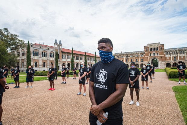 Masked Rice football players standing in the quad