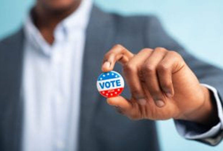 Person in suit holding a vote button in their hands. 