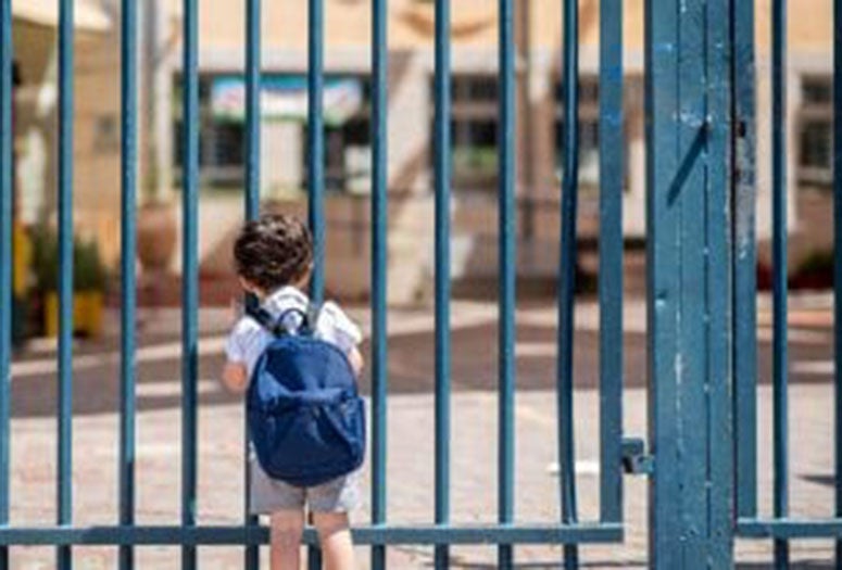 Child standing at schoolyard gate