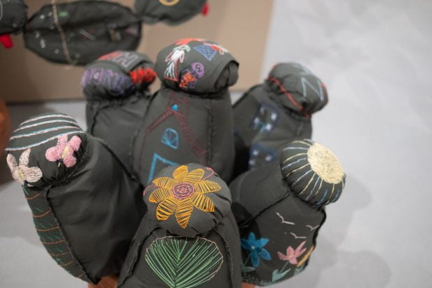 Margarita Cabrera’s “Space in Between” repurposes U.S. Border Patrol uniforms into cacti, agave and aloe vera “plants” growing out of terra cotta pots.