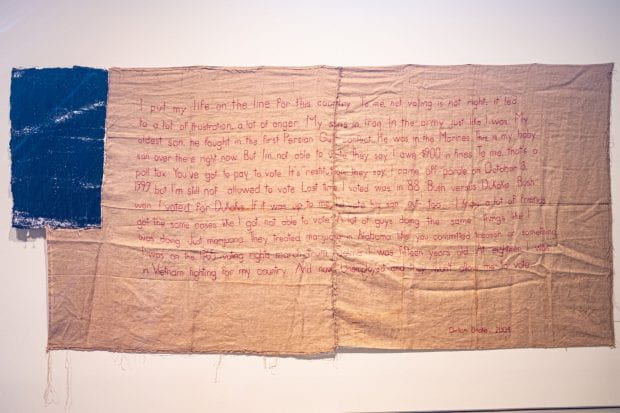 Clinton Drake's words are embroidered with red thread on McMillian’s “Untitled (flag IV).”