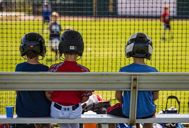 Boys sitting watching baseball. 