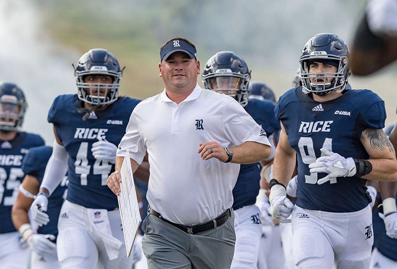Rice football team running with coach