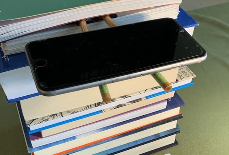 iPhone being held up by pencils and books