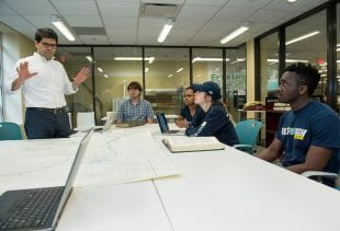 Domingues works with a class of Rice students studying maps of the west coast of Africa. (Photo by Jeff Fitlow)