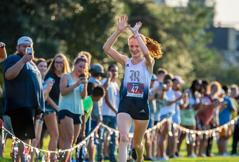 Grace Forbes celebrates as she nears the finish line during the Rice Invitational (Photo by Tommy LaVergne)