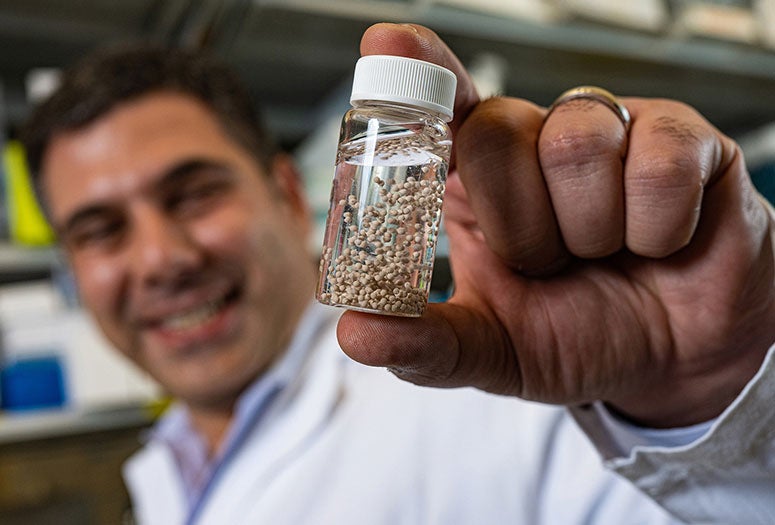 Rice University bioengineer Omid Veiseh with a vial of bead-like implants his lab invented to serve as anti-cancer drug factories