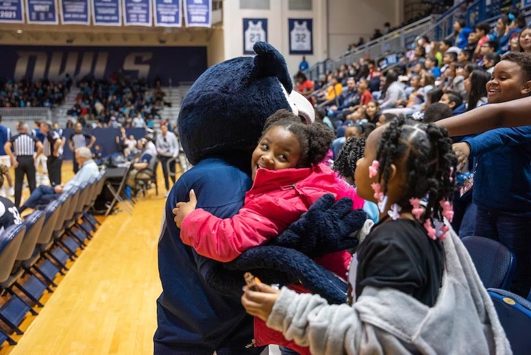 A child hugs Sammy the Owl during School House Mania at Tudor Fieldhouse at Rice University.