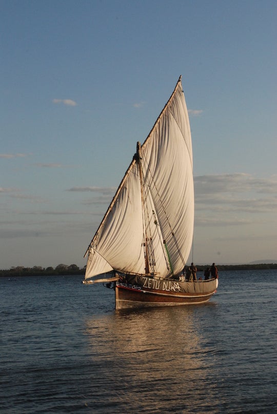 wooden boat with large white sail 