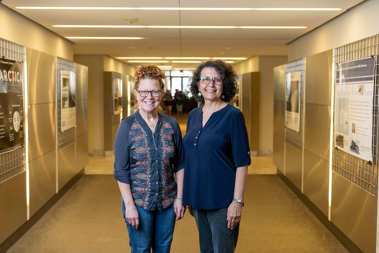 Linda Welzenbach-Fries and Ipek Martinez pose for a photo in front of a new exhibit in Fondren Library that features photos from Fries' explorations to Antarctica.