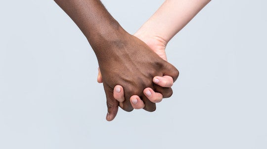 Photo of Black and White hands holding. 