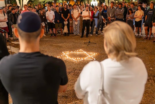 A Star of David made of small candles amid a crowd of vigil attendees.