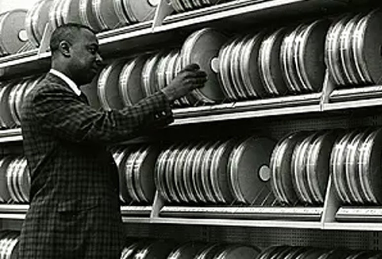 Computer specialist John Smith arranges and examines cannisters of magnetic tape used in the processing of medical data at the National Library of Medicine