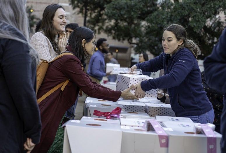 Cam Zapater, right, program administrator in the Office of Graduate and Postdoctoral Studies, hurries to distribute cakes to graduate students at the annual Take the Cake celebration, where about 100 graduate students received 102 cakes, one for each of the major external fellowships they received.
