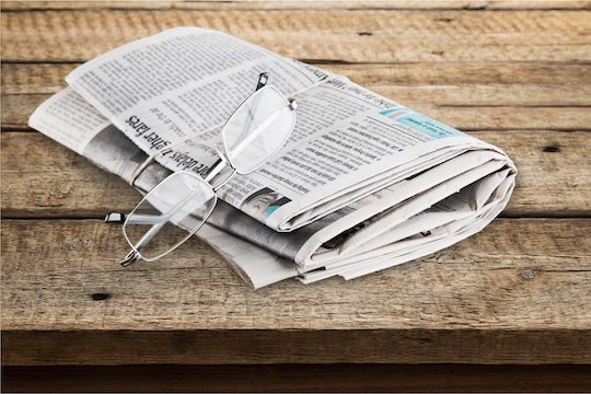 Photo of a newspaper with a pair of eyeglasses on top.