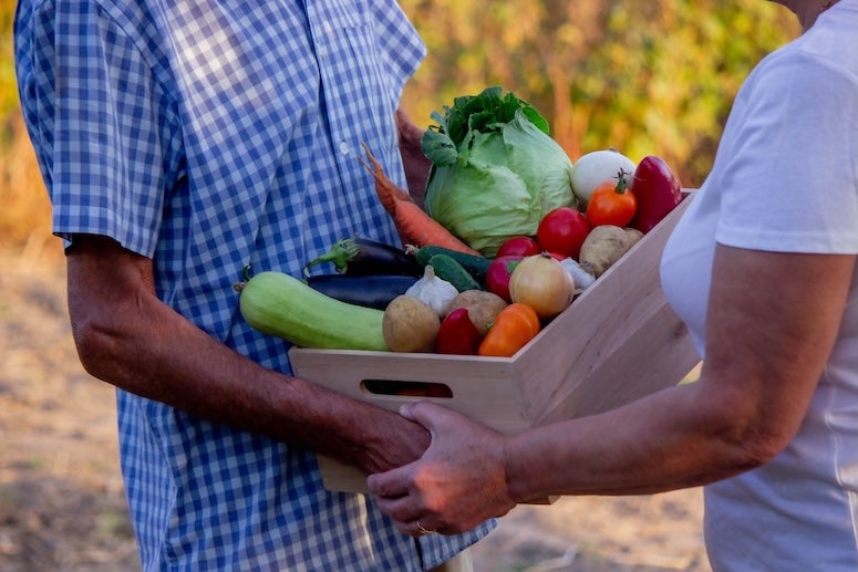 Farmers exchanging a box of food. 