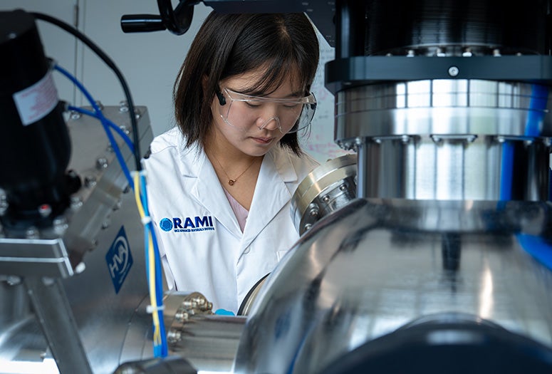 female researcher wearing lab coat operating large instrument