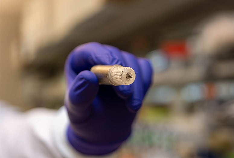 gloved hand holding a small device