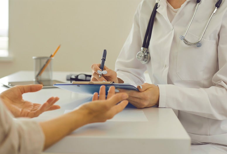 Female therapeutist with clipboard listening to patient and noting down her health complaints