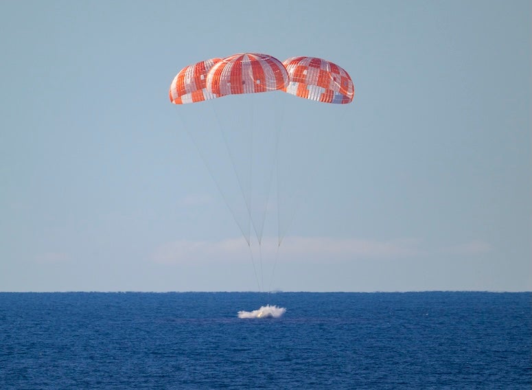 NASA's Orion spacecraft landing in the ocean: three striped parachutes landing on blue water
