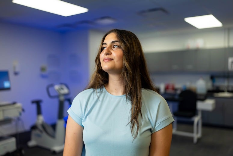 A Latina woman with long wavy brown hair looks upward with a slight smile