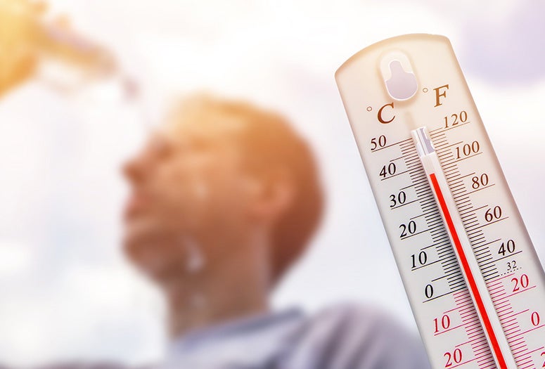 stock image featuring thermometer showing high temps and man pouring water bottle over his head