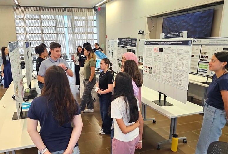 poster presentation session with students listening to a presenter