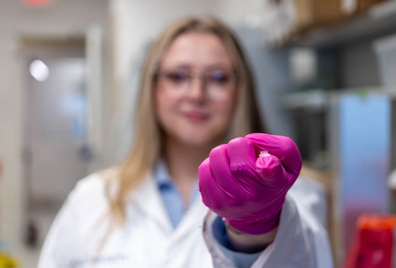 pink-gloved research holding wound patch