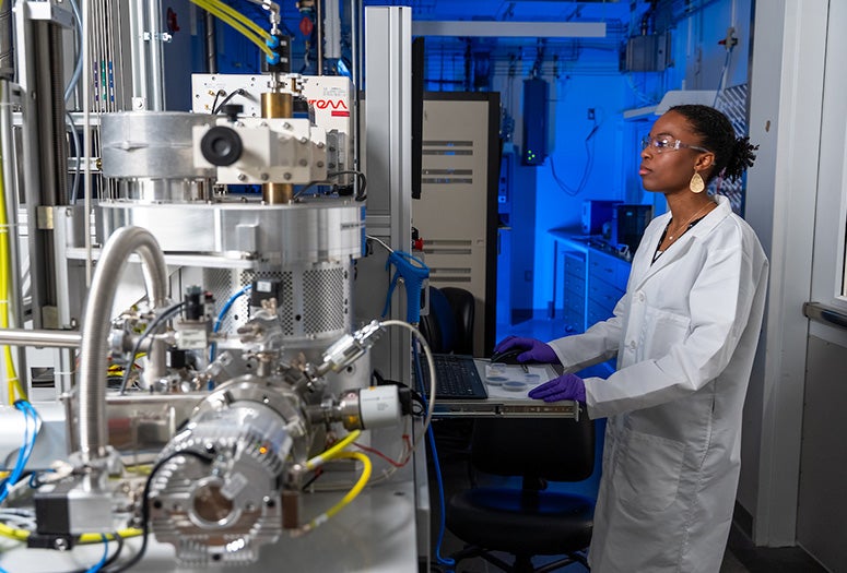 black female researcher in lab coat interacts with research equipment