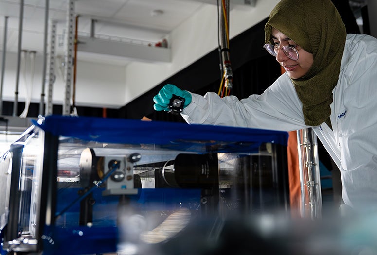 researcher in lab coat interacting with equipment