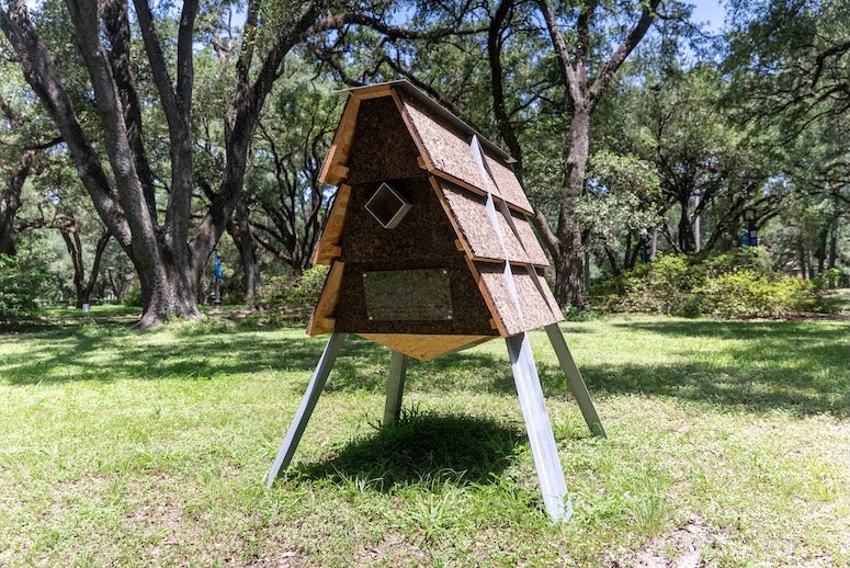 A small triangular prism on stilt legs leans gently to the right
