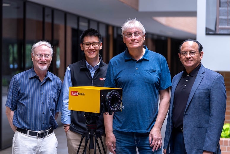 Four men stand outside around a yellow box. 