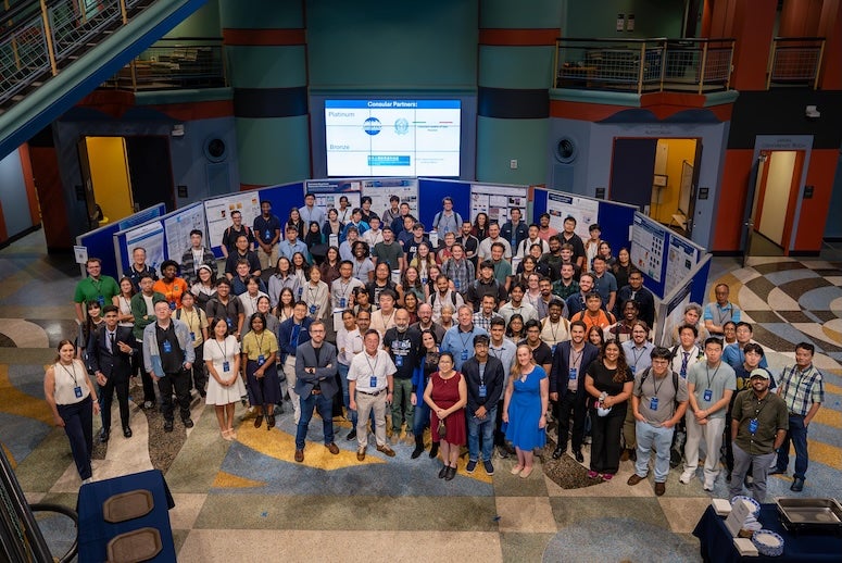 A large group of people stands in front of posters