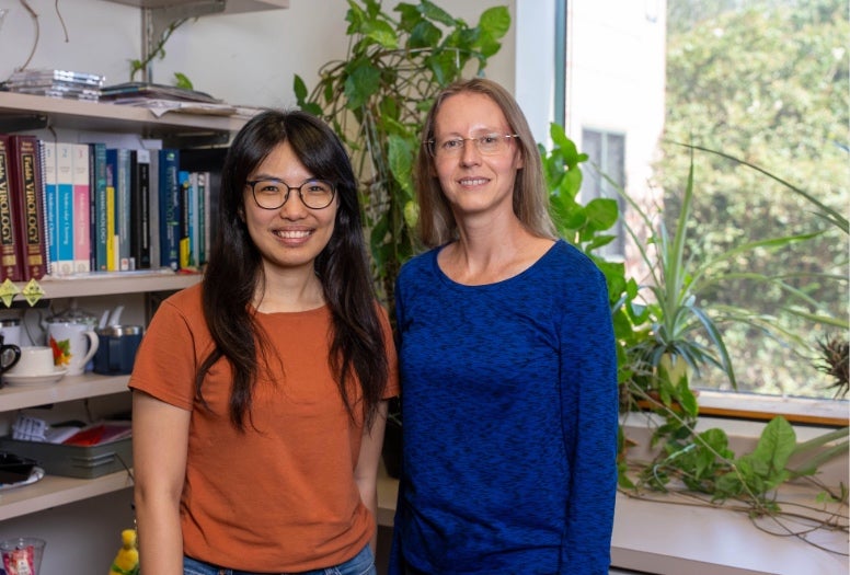 An Asian woman stands next to a white woman. 