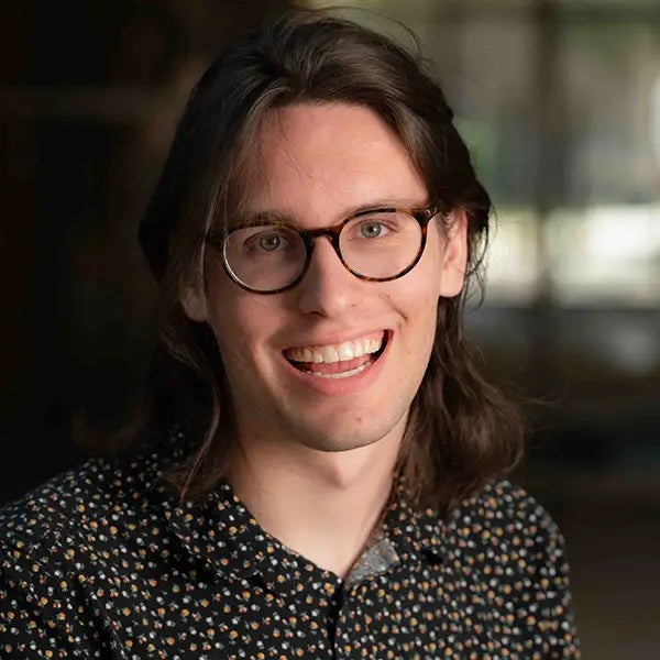 A young white man smiles at the camera