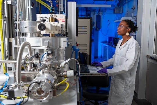 black female researcher in lab coat interacting with research equipment