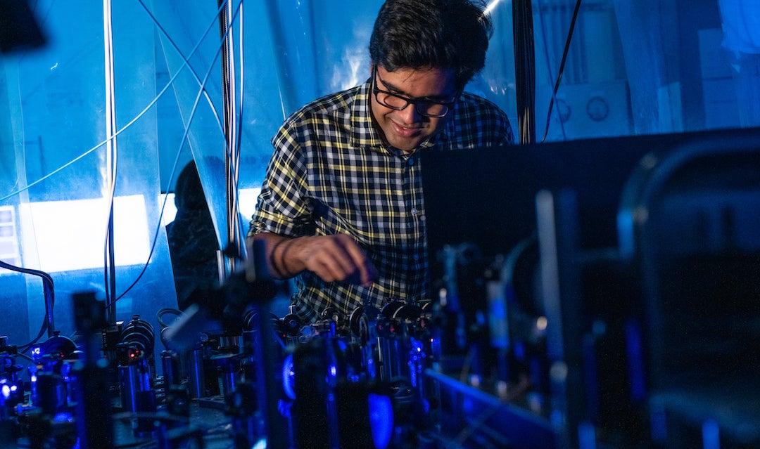 Rice University graduate student Soumya Kanungo works at a laser platform with the array of instruments he and a team used to manipulate electrons in Rydberg atoms to create “synthetic dimensions,” stand-ins for extra spatial dimensions that could be useful in quantum research. (Credit: Jeff Fitlow/Rice University)