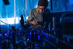 Rice University graduate student Soumya Kanungo works at a laser platform with the array of instruments he and a team used to manipulate electrons in Rydberg atoms to create “synthetic dimensions,” stand-ins for extra spatial dimensions that could be useful in quantum research. (Credit: Jeff Fitlow/Rice University)