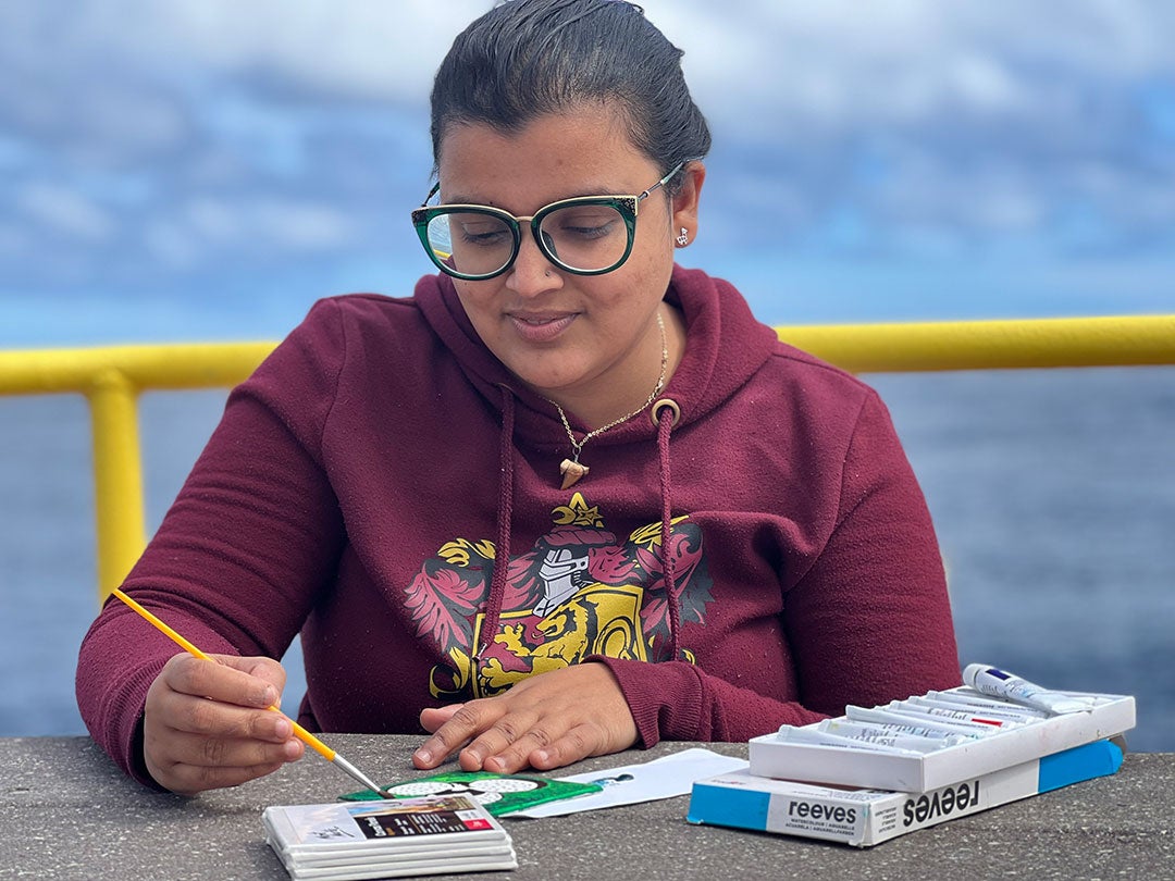 Debadrita Jana painting microfossils on the upper deck of the research vessel JOIDES Resolution in February 2022