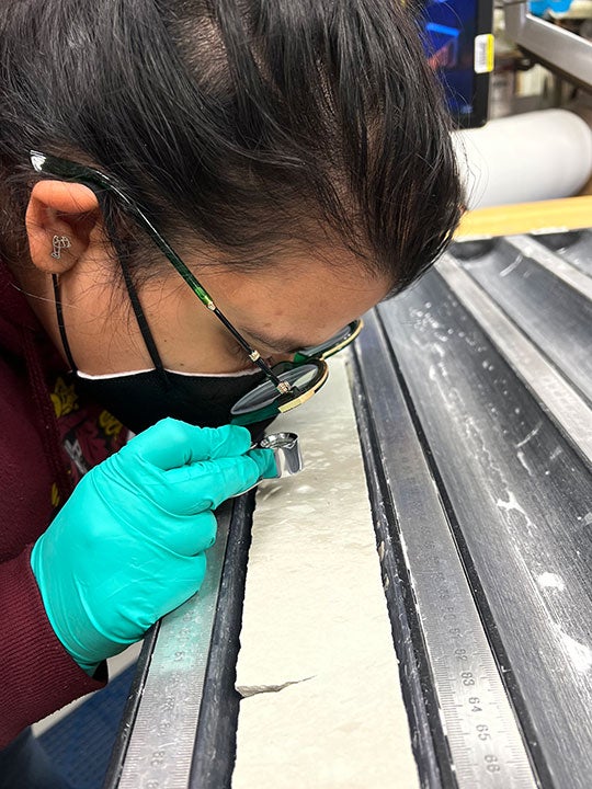 Rice Ph.D. student and JOIDES Expedition 392 crewmember Debadrita Jana examining sediment cores for microfossils aboard the research vessel JOIDES Resolution in February 2022