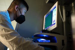 Graduate student Qichen Yuan checks the cells in an array at a Rice University lab. Yuan is the lead author of a study introducing a streamlined CRISPR-based technology that can perform many genome edits at once to address polygenic diseases. (Credit: Jeff Fitlow/Rice University)