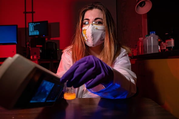 Rice graduate student Ashleigh Smith McWilliams holds a vial of fluorescing boron nitride nanotubes. She led a study to capture video of the nanotubes in motion to prove their potential for materials and medical applications. Photo by Jeff Fitlow
