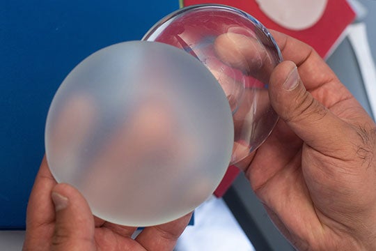 Rice University bioengineer Omid Veiseh shows silicone breast implants with rough (left) and smooth surfaces. (Photo by Jeff Fitlow/Rice University)