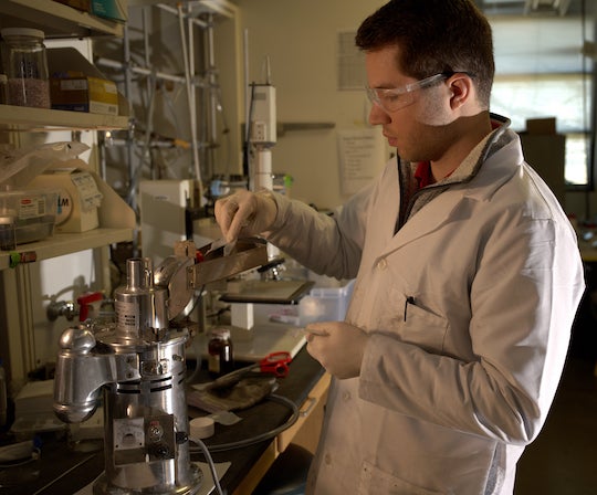 Rice University graduate student Paul Savas feeds raw plastic into a crusher to prepare it for pyrolysis, or heating in an inert atmosphere. Pyrolyzing the material in the presence of potassium salts turns it into a material that sequesters carbon dioxide from flue gas. (Credit: Jeff Fitlow/Rice University)